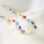 Zoom sur le collier ras-du-cou perlé, perles rondes de qualité et détails géométriques.