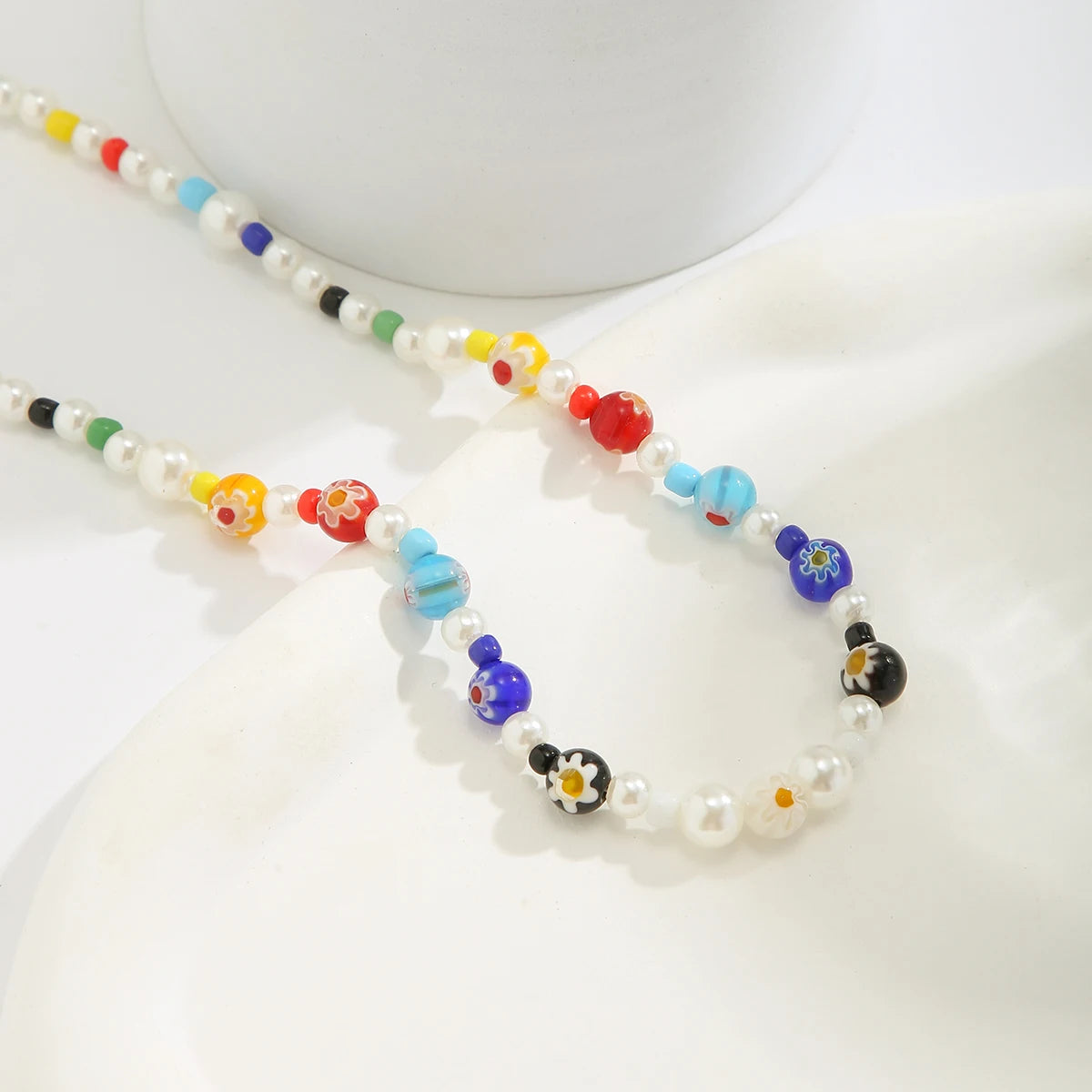 Zoom sur le collier ras-du-cou perlé, perles rondes de qualité et détails géométriques.